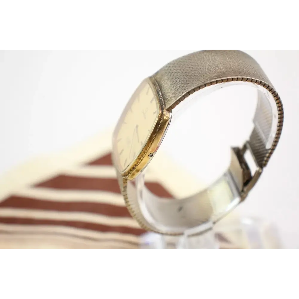 Close-up of a gold and silver watch with a textured band on a white background