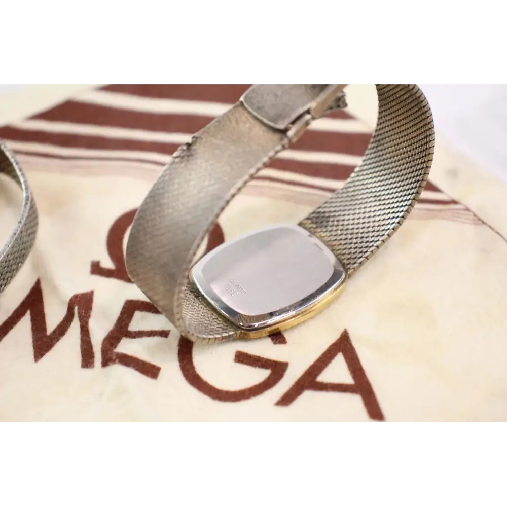 Silver watch with mesh band on a branded cushion