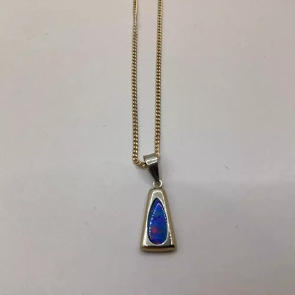 Gold necklace with a triangular pendant featuring blue and red colors on a light gray background