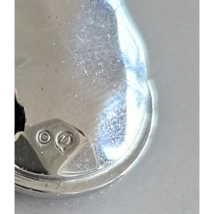 Close-up of a silver object with visible hallmarks on a gray background