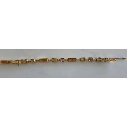 Gold bracelet with pink stones on a white background