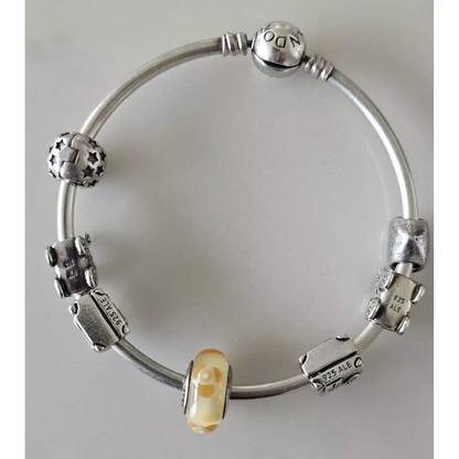 Silver bracelet with various charms on a light gray background
