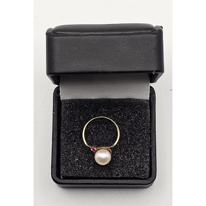 Gold ring with a pearl and ruby in a black jewelry box
