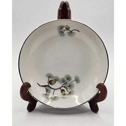 Ceramic bowl with pine branch design on a wooden stand 
