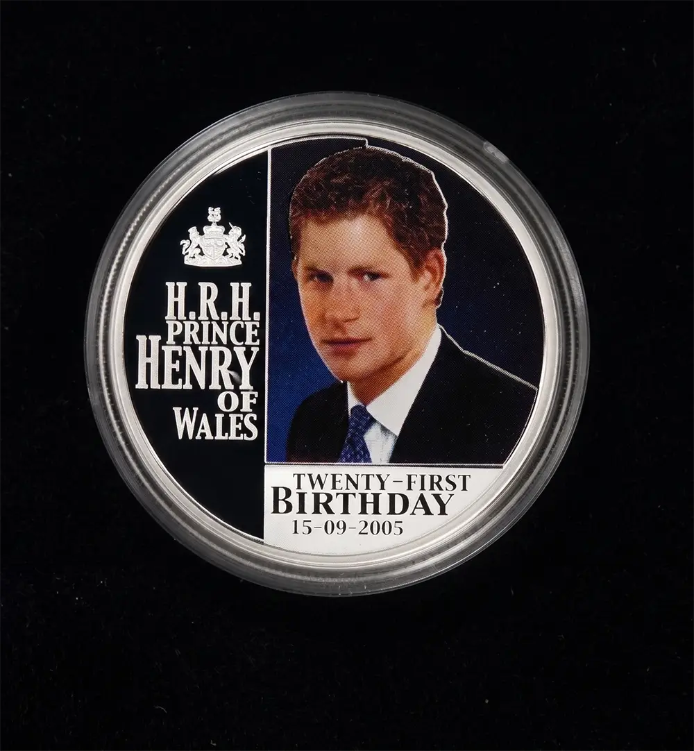 A round commemorative coin in a clear protective case, featuring a portrait of Prince Henry of Wales with the text 'H.R.