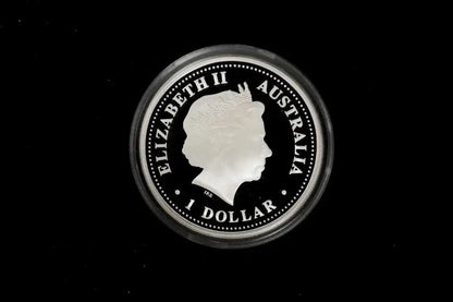 A circular silver coin of Queen Elizabeth II of Australia, 1 Dollar, encased in a clear protective plastic capsule, set against a solid black background.