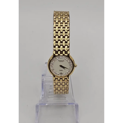 Gold wristwatch with a clear stand on a gray background