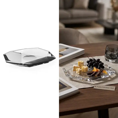 A clear faceted glass serving platter shown on a white background on the left, and styled on a wooden table with cheese, grapes, and a glass on the right in a real interior setting.