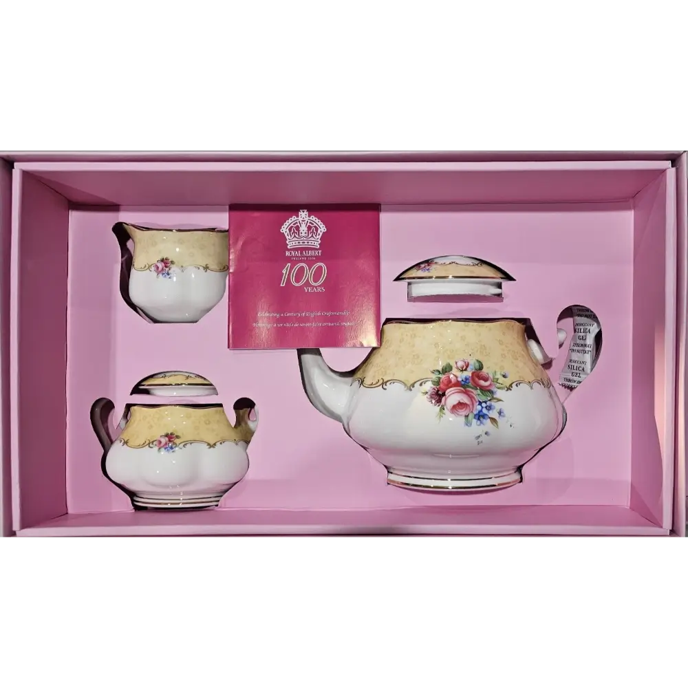 Tea set with floral designs in a pink box, featuring a card with a crown and text.