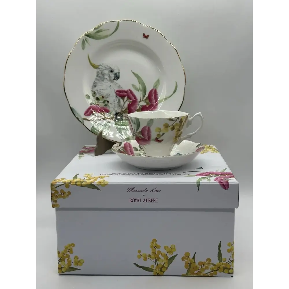 Tea cup and saucer set with floral design on a matching box against a gray background