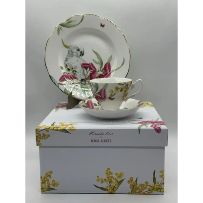 Tea cup and saucer set with floral design on a matching box against a gray background