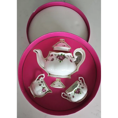 Set of ceramic tea set with floral design on a pink cushioned tray