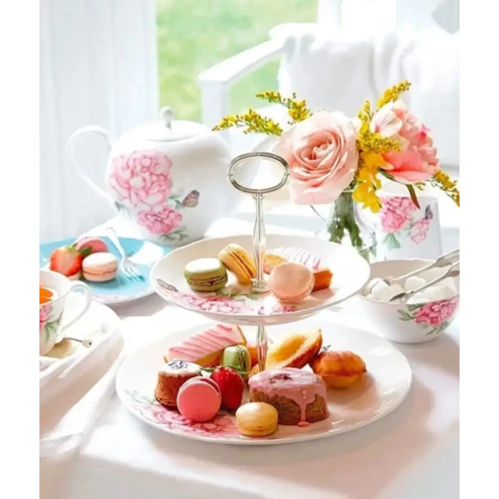 Tea party setup with pastries, teacups, and floral decorations on a table.