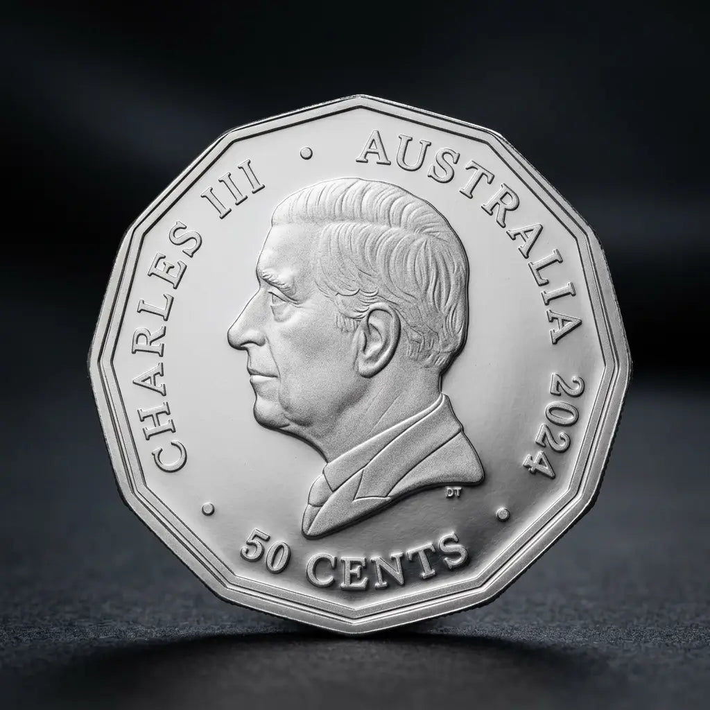 A silver Australian 50 cents coin featuring a profile portrait of Charles III, photographed on a dark, reflective surface.