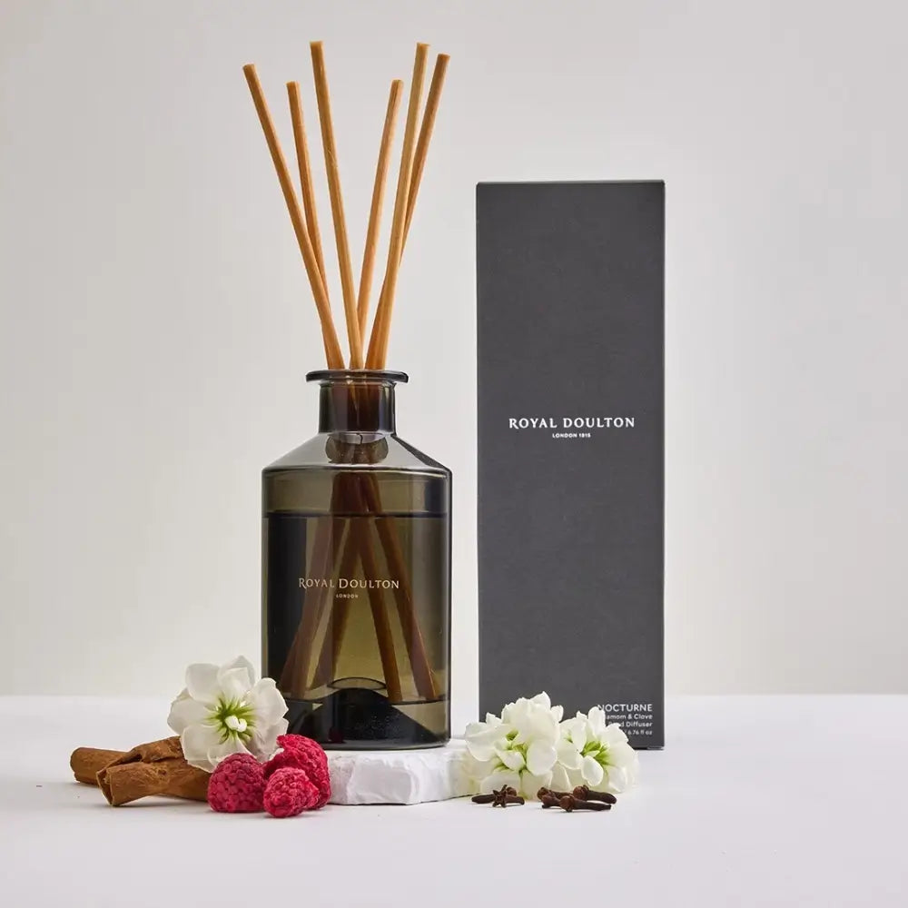 Royal Doulton diffuser with reeds, flowers, and cinnamon sticks on a white background