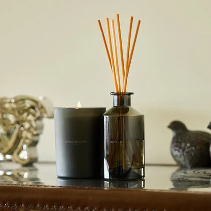 Candle and diffuser with wooden sticks on a reflective surface