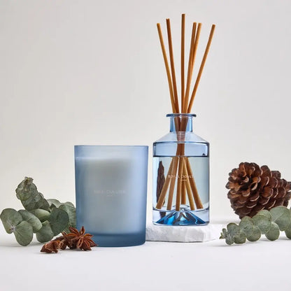 Blue candle and diffuser with natural elements on a light background