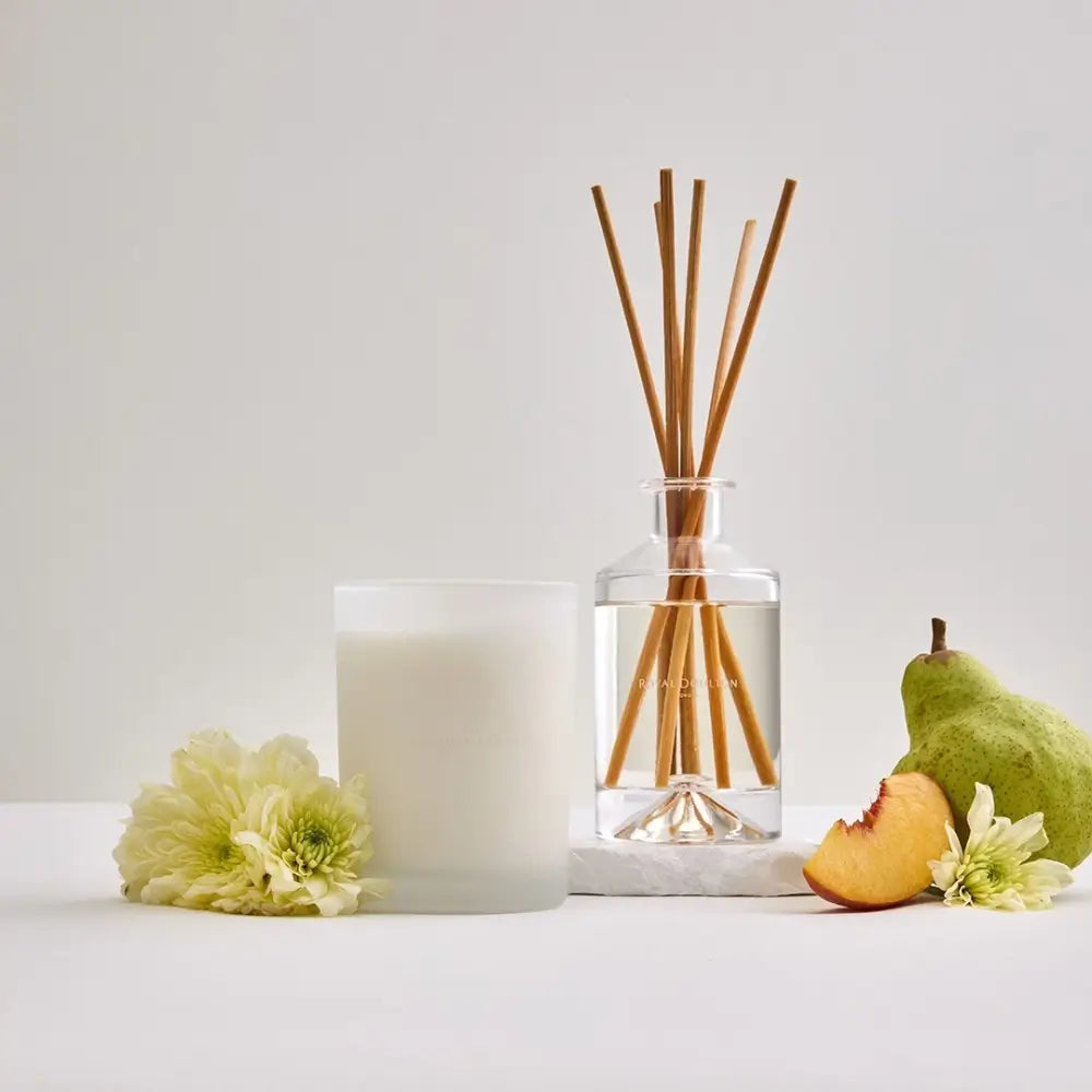 Candle and diffuser with fruits and flowers on a light background