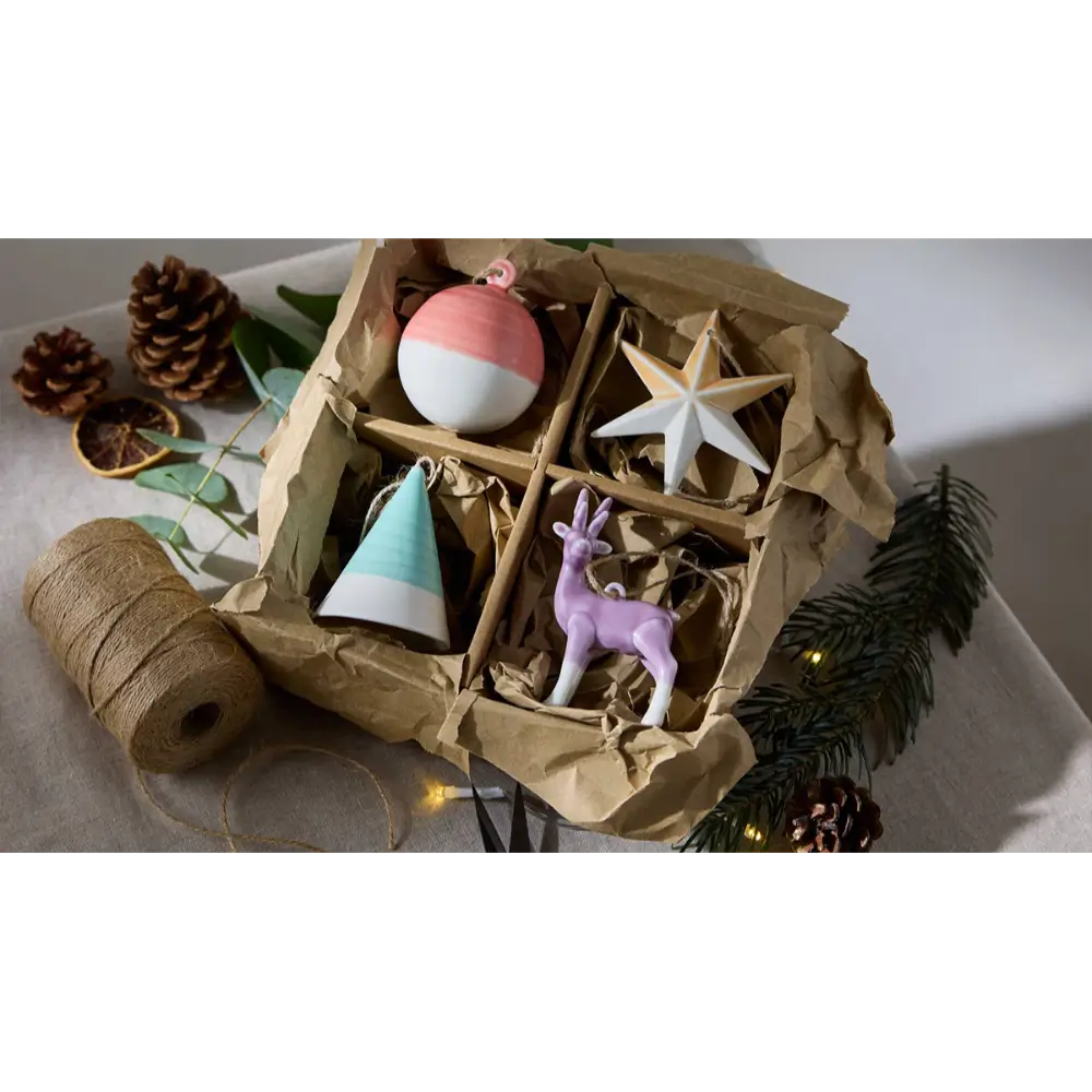 Decorative items including a pink and white ornament, star, cone, and deer figurine in a box 