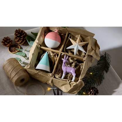 Decorative items including a pink and white ornament, star, cone, and deer figurine in a box 