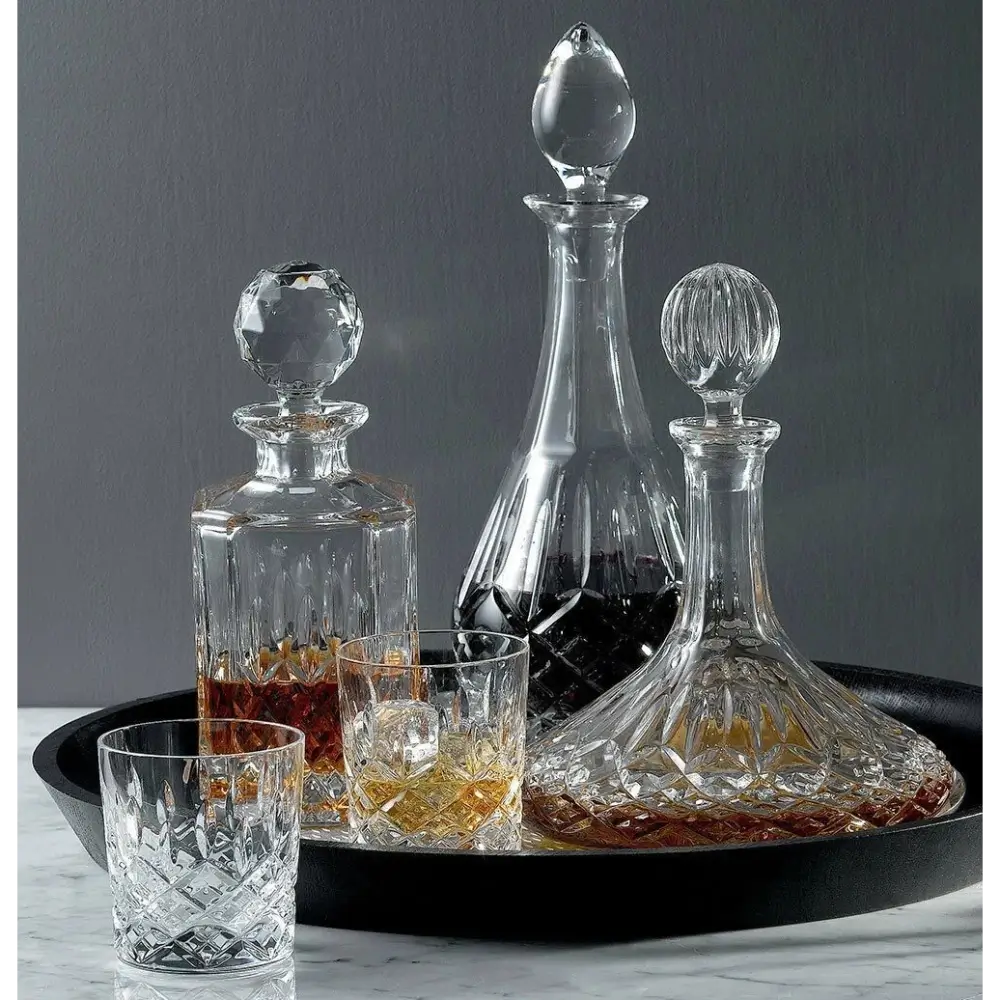Set of glass decanters and glasses on a dark surface with a gray background