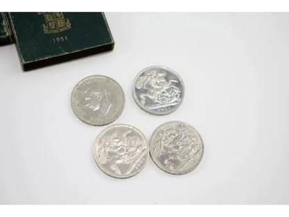 Four silver coins on a white surface with a green box in the background.