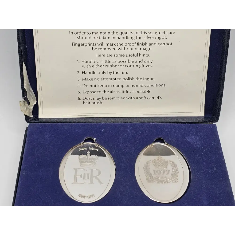 Two silver medals in a case with a care instruction leaflet.