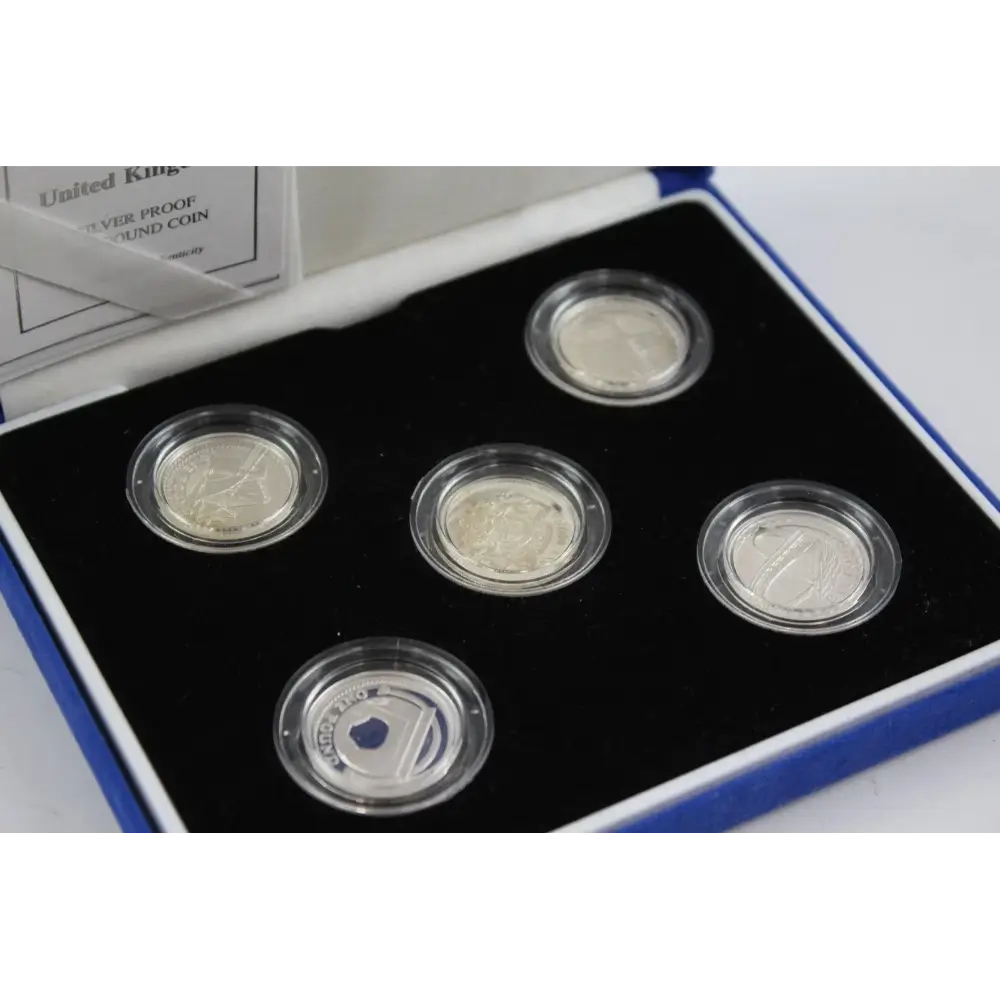 Set of five silver coins in a display case with a visible brand logo.