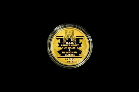 A round gold commemorative coin in a clear protective capsule, centered on a solid black background. The coin features black text and a black crest with the text 'H.