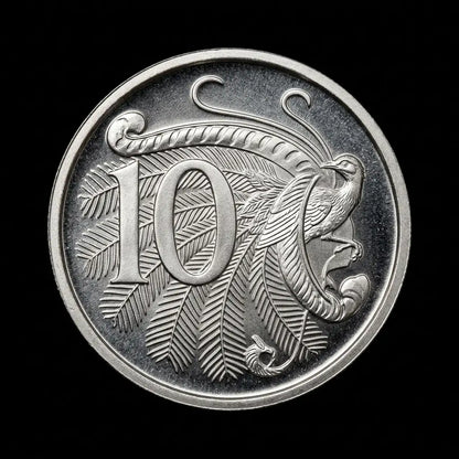 A circular silver coin featuring a large engraved number 10 and a bird motif with leaf-like patterns, shown against a solid black background.