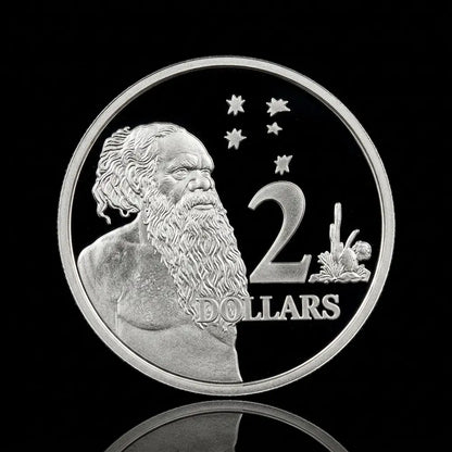 A round silver coin featuring a portrait of an Aboriginal man with a long beard, stars, a large '2', and the word 'DOLLARS', shown on a black reflective background.