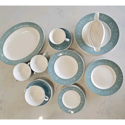 Collection of white ceramic dishes with green decorative rims on a light gray surface.