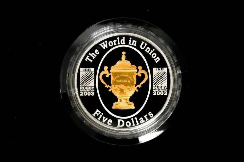 A circular black and gold Rugby 2003 five-dollar coin featuring the World in Union trophy emblem, encased in a clear protective plastic capsule from our World & Vintage Coins collection 