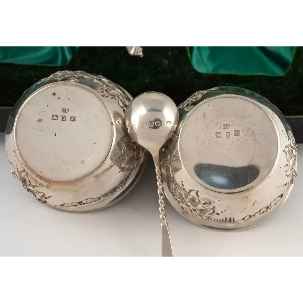 Two silver items with engraved details on a white surface
