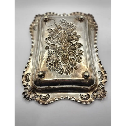 Decorative silver tray with floral patterns on a gray background