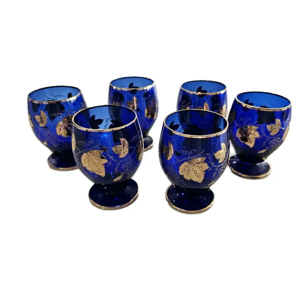 Set of six blue glasses with gold leaf patterns on a white background