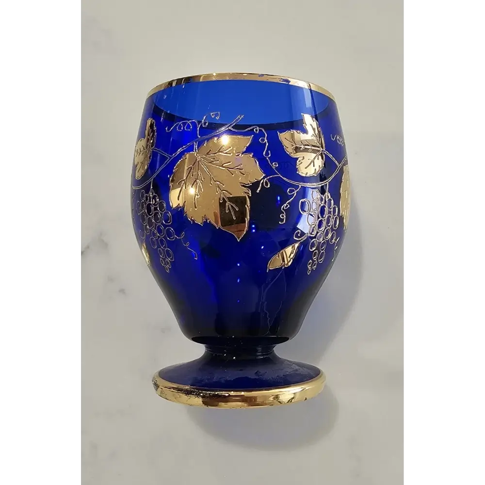 Intricate 24K gold gilt grape leaf and vine motif on a deep cobalt blue Bohemian glass goblet.