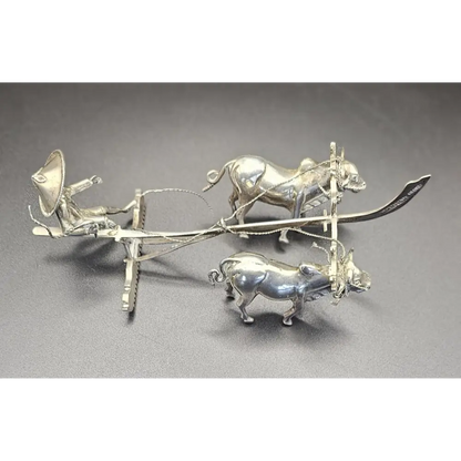 Silver plow with oxen on a gray background