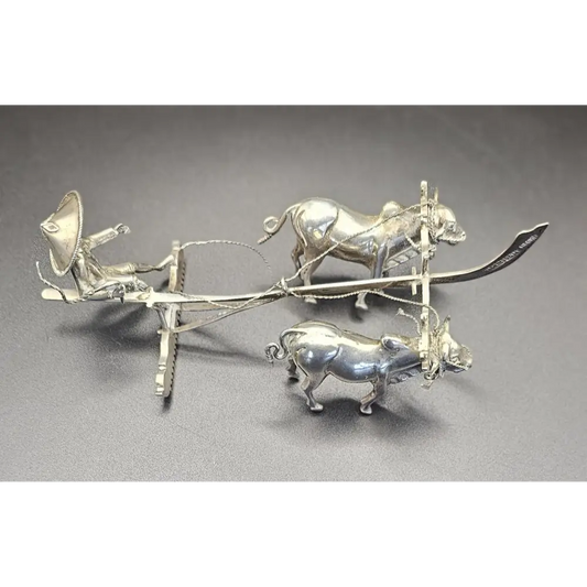 Silver plow with oxen on a gray background