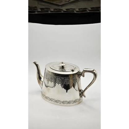 Silver teapot with intricate designs on a white background