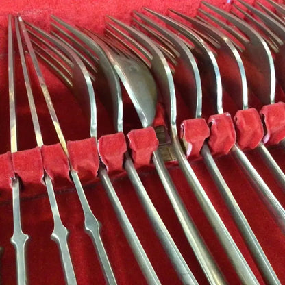 Set of silver dessert forks on a red cushion