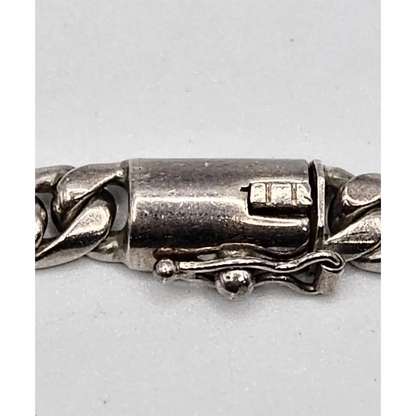 Close-up of a silver bracelet clasp on a light gray background