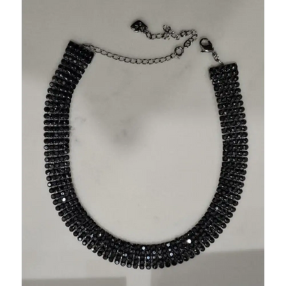 Black beaded necklace on a white marble surface