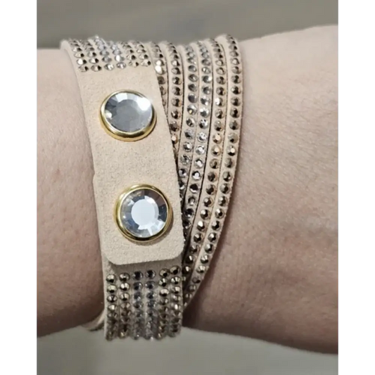 Beige leather wrap bracelet with rhinestones on a wrist against a neutral background