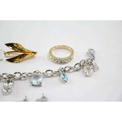Jewelry items including a gold brooch, ring, and bracelet with charms on a white background