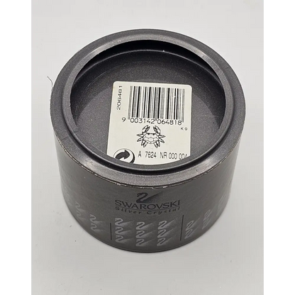 Gray metal component with a barcode label and Swarovski branding on a white background