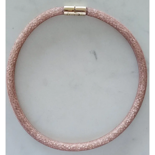 Pink glittery bracelet with a gold clasp on a light gray background