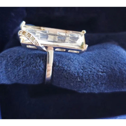 Gold ring with a large rectangular gemstone on a blue cushion