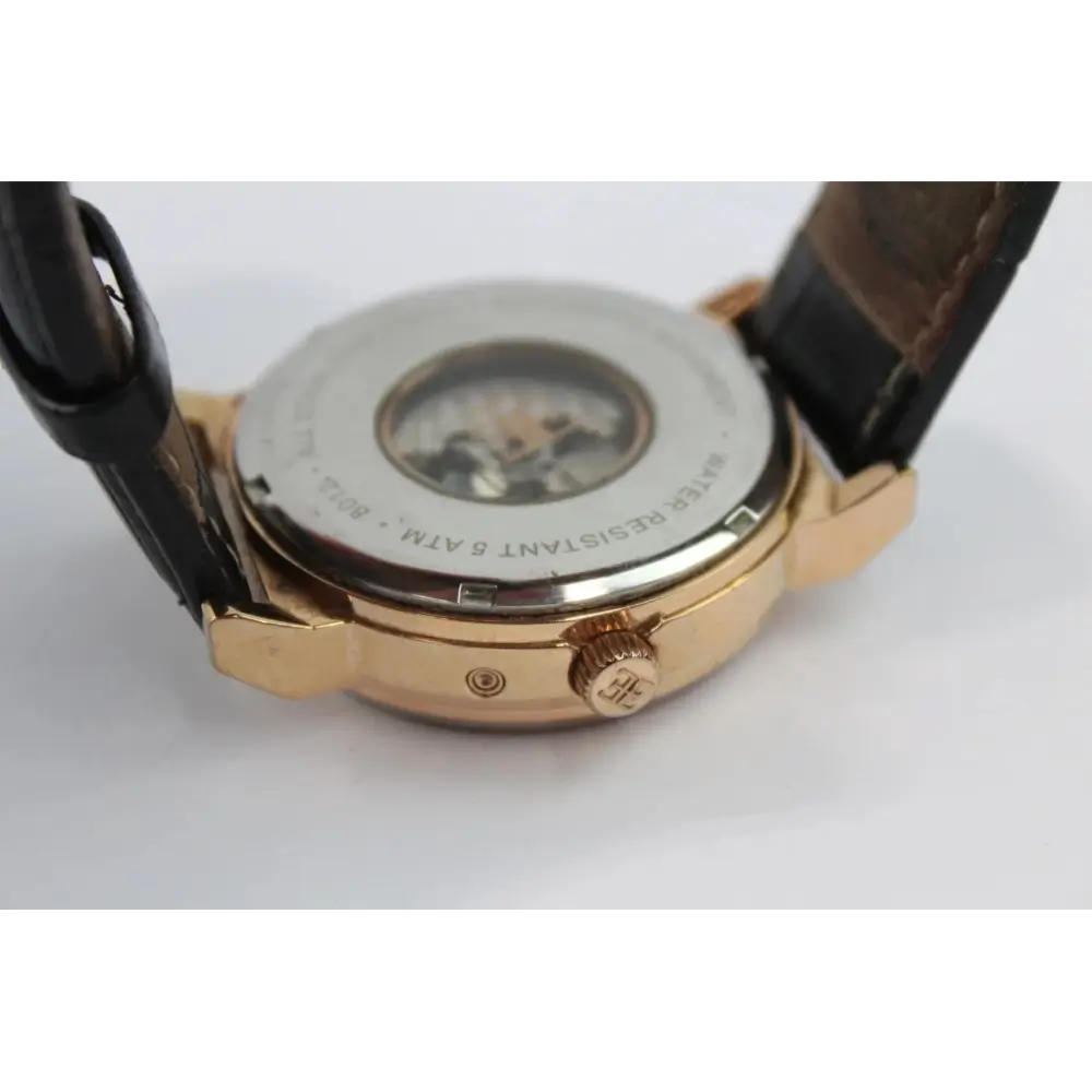 Close-up of a watch with a gold case and brown leather strap