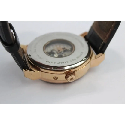 Close-up of a watch with a gold case and brown leather strap